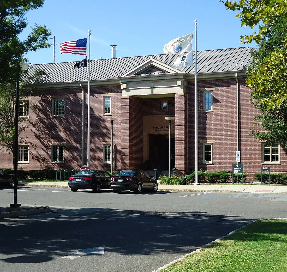 A brick city hall with flags flying outside the main entrance