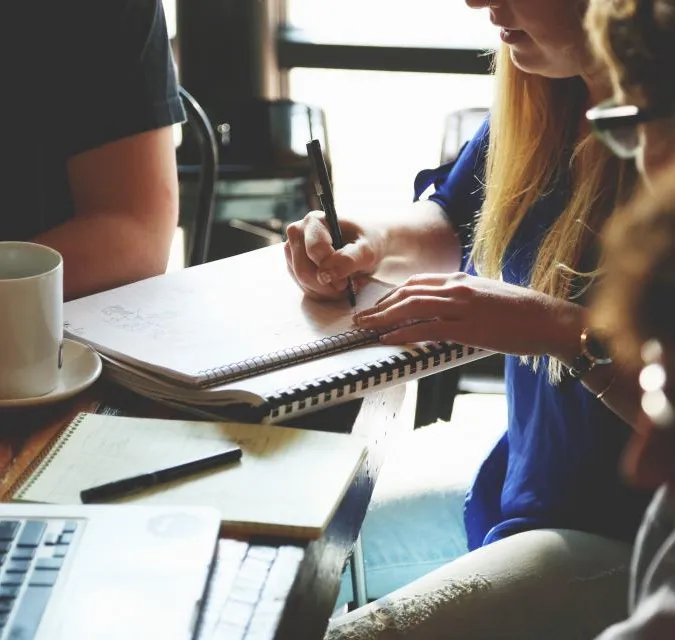 A small team working together over notebooks and a laptop